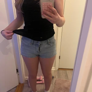 Ljusblå jeansshorts från Perfect Jeans - Säljer ett par ljusblå jeansshorts från Perfect Jeans i storlek 34. De har råa, fransiga kanter och klassisk femficksdesign. Shortsen är midwaist och har en avslappnad passform, perfekta för varma dagar.