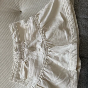 Vit jeanskjol med volangdetalj - Säljer en vit kort jeanskjol med volangdetalj och klassiska fickor fram❣️
