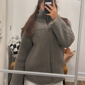 Brun teddyjacka  - Brun teddyjacka från Gina Tricot med hög krage och hel dragkedja framtill. Jackan har en loose passform och är i teddy-material som håller dig varm. Använd 2 gånger, perfekt för höst och vinter 🍁❄️