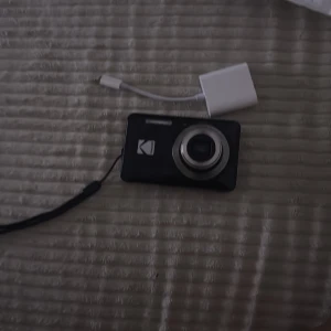 Kodak kompaktkamera - Smidig Kodak digitalkamera med asfäriskt zoomobjektiv. Kameran är i gott skick med endast mindre spår av användning. Perfekt för dig som vill ha en enkel och pålitlig kamera för vardagsfotografering. Handledsrem och adapterkabel medföljer.