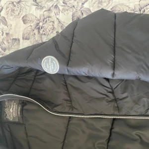 Priser kan diskuteras  - Säljer en svart pufferjacka från Jack & Jones Originals. Jackan har quiltad design, dragkedja framtill och en snygg badge på ärmen. Perfekt för kyliga dagar och har en modern, clean look. Materialet är syntet och jackan är lätt vadderad för extra värme.