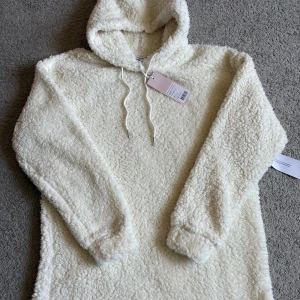 Vit teddyhoodie med huva från Bubbleroom - Supermjuk och fluffig teddyhoodie i krämvit färg från Bubbleroom. Hoodie har huva, snörning och lång ärm. Perfekt för dig som vill ha en cozy och trendig look under kyliga dagar.