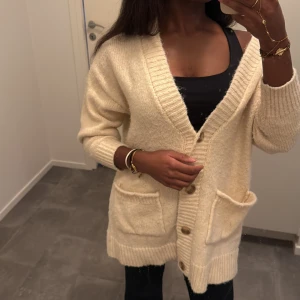 Stickad kofta med fickor - Mysig beige stickad kofta med grov ribbad kant och stora framfickor. Koftan har v-ringad hals, knappar framtill och långärmade ärmar ❄️🎀