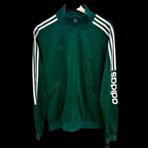 Adidas träningsset herr M – nästan nytt - Snyggt Adidas set i mörkgrönt med klassiska vita ränder. Både jacka och byxor i matchande stil. Storlek M.  Använt endast 2–3 gånger – ser ut som nytt! Byxorna har praktiska fickor på sidorna och jackan har dragkedja samt fickor.  Detta är ett riktigt bekvämt och stilrent set som passar både till vardags och träning.  💚 Adidas original 💚 Trendig färg 💚 I toppskick