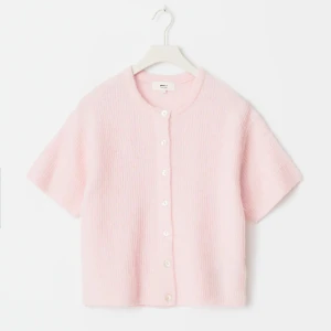 Ljusrosa stickad kofta med kort ärm - Superfin ljusrosa stickad kofta från Other Stories med korta ärmar och rund hals. Koftan har knappar framtill och är gjord i ett mjukt material som känns fluffigt och mysigt. Perfekt för vår och sommar när du vill ha något lätt men ändå gulligt.