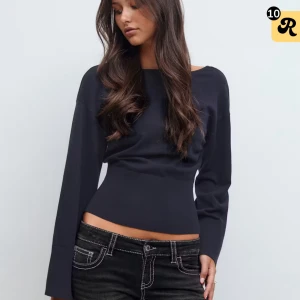 Svart topp med öppen rygg och lång ärm - Snygg svart topp med lång ärm och markerad midja. Toppen har en bred, rundad halsringning fram och en djup v-ringning i ryggen som ger en öppen rygg-effekt. Materialet är mjukt och stretchigt, perfekt för en trendig look. Använd en gång