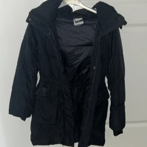 Svart vinter jacka från Mckinley i storlek 146 så liksom det passar till S  - Svart vinterjacka från Mckinley. Den är lång och fin håller sig också varm. Har en fin luva. Man kan ta fram reflex vid händerna om man vill som på bilden. Den är använd men inga farliga märken. Det sticker bara ut lite fjädrar här och där på vissa ställen. Om ni vill se vart det sticker ut fjädrar kan ni gärna skriva till mig. Så tar jag nya bilder. 