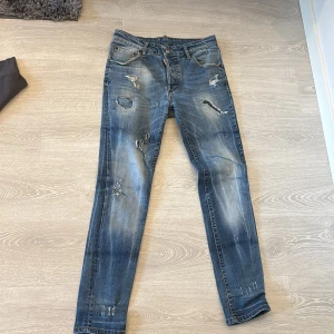 Dsquared2 blå slitna jeans, stl 46 - Riktigt snygga blå jeans från Dsquared2 med slitningar och trasiga detaljer framtill. Jeansen har klassisk femficksdesign, normal passform och är tillverkade i bomull. Perfekt för dig som gillar en cool och avslappnad streetstil.