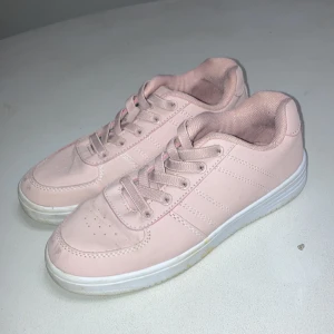 Ljusrosa sneakers från Andy - Snygga ljusrosa sneakers från Andy by Frank Dandy med vita detaljer och klassisk låg profil. Skorna har snörning, rund tå och platt sula. Materialet är syntet med textilfoder och diskreta sömmar längs sidorna. Perfekt för dig som gillar stilrena och softa färger.