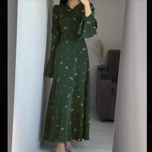 Mörkgrön långklänning med blommor - Snygg mörkgrön långklänning med små vita blommor, v-ringad hals och långa ärmar. Aldrig använt. Shein storlek L. Men är liten i storlek så passar M. 