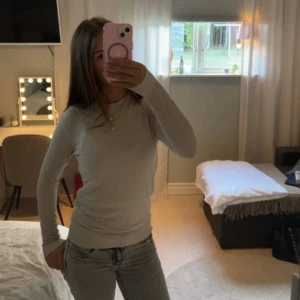 Vit långärmad tröja i bomull - Säljer en enkel och stilren beige långärmad tröja i fin stickat. Tröjan har rund hals och en normal passform som sitter snyggt på kroppen. Perfekt att matcha med jeans eller kjol för en clean look.