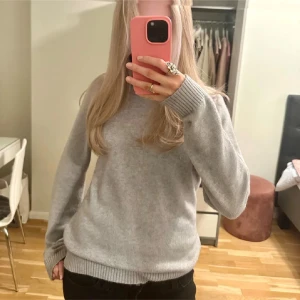 Grå stickad tröja från Vila - Mysig grå stickad tröja från Vila med rund halsringning och ribbade muddar vid ärmslut och nederkant. Perfekt för lager-på-lager och enkel att matcha till olika outfits. Klassisk modell med lång ärm och normal passform.