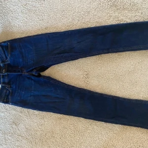 Jack & Jones Slim Glenn jeans blå 29/30 - Mörkblå jeans från Jack & Jones, modell Slim Glenn. Snygg slim fit med klassiska detaljer och kontrastsömmar. Tillverkade i bomull med en skön stretch. Perfekta för dig som gillar en smalare passform och stilren look.