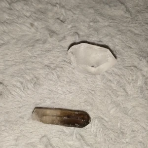 Kristaller  - Bilden visar två kristaller, en klar bergskristall och en rökfärgad kristall 