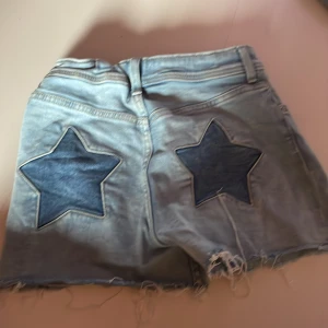 Fina denim shorts - Snygga denim shorts med stjärndetaljer på bakredelen med snygga slitna endar av shortsen! Perfekt för en varm dag med en cool vibe.