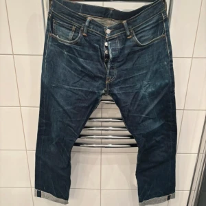Levi's 501 selvedge  W34 L32 - Mörkblå klassiska Levi's 501 jeans med raka ben och knappgylf. Snygga kontrastsömmar och fem fickor. Ikonisk läderpatch baktill och röd Levi's-tag på bakfickan. Jeansen är tillverkade i slitstarkt bomullsdenim och har en tidlös look.