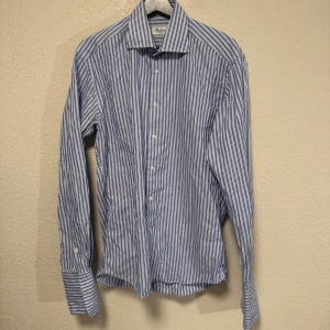 Blårandig skjorta från Stenströms - Snygg skjorta från Stenströms i fitted body-modell, med klassiskt blårandigt mönster och vit knappstängning. Skjortan har lång ärm, krage och är gjord i mjuk bomull som känns skön mot huden. Perfekt för dig som gillar stilrena och fräscha plagg.