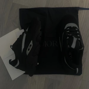 Dior B22 - Säljer ett par svarta sneakers från Dior med grå och vita detaljer. Skorna har en chunky sula, meshpartier och snörning framtill. Perfekta för dig som vill ha en lyxig och sportig look. Kommer med originalpåse. Sköna för vintern 10/10