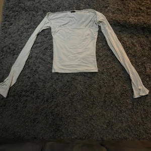Vit långarmad topp från Gina Tricot - Säljer en vit långärmad topp från Gina Tricot i storlek S. Toppen har långa ärmar och är figurnära med en stilren, enkel design. Materialet är mjukt och stretchigt, perfekt för dig som gillar minimalistisk stil och vill ha en topp som sitter snyggt.