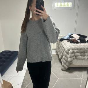 Grå stickad tröja från Gina Tricot - Mysig grå stickad tröja från Gina Tricot i oversized modell. Tröjan har rund halsringning, långa ärmar och ribbade muddar vid ärmslut och nederkant. 