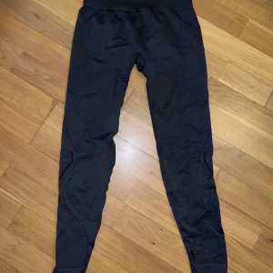 Svarta leggings från BLACC Yoga S - Svarta leggings från BLACC Yoga i storlek small. De har hög midja och diskreta mönsterdetaljer längs benen. Materialet är stretchigt och passar perfekt för yoga eller träning. Snygg och bekväm passform som sitter tight mot kroppen.
