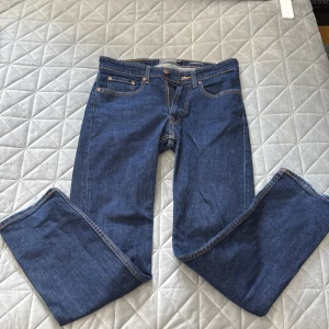 Blå jeans från Dressmann Regular Fit - Snygga blå jeans från Dressmann i modellen Regular Fit. Klassisk femficksdesign med raka ben och kontrastsömmar. Jeansen har normal passform och är tillverkade i slitstarkt denimtyg som ger en tidlös look.