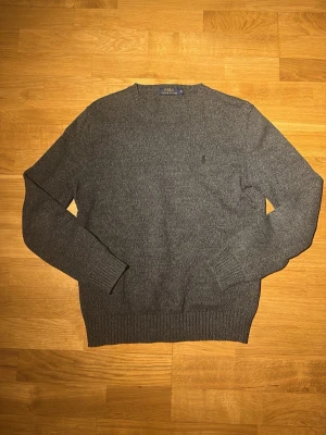 Grå stickad tröja Polo Ralph Lauren - Säljer en snygg Mörkgrå stickad tröja från Polo Ralph Lauren i storlek S. Klassisk modell med rund halsringning, ribbade muddar och diskret broderad logga på bröstet. Storlek S. inga defekter. Hör av dig vid frågor eller prisförslag…