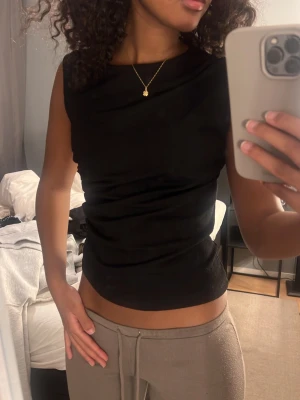 Svart ärmlös linnetopp - Säljer en svart, stilren linnetopp med rund halsringning och figurnära passform. 