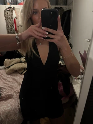 Svart kort klänning med v-ringning - Säljer en svart kort klänning med djup v-ringning och ärmlös design. 