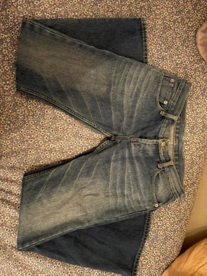 Levi's bootcut jeans - Klassiska Levi's jeans i blå tvätt med snyggt slitna detaljer och raka ben. Jeansen har gylf med knappar och den ikoniska röda Levi's-lappen på bakfickan. Perfekt för dig som gillar tidlös denimstil. 