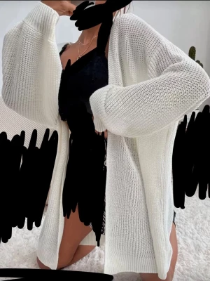 Vit lång stickad kofta - Lång, oversized kofta i vit stickad kvalitet. Koftan har breda ärmar och en öppen front utan knappar eller dragkedja. Perfekt att slänga över en topp för en chill och avslappnad look. Passar till både jeans och klänning. Jätte cozy btw så de kliar inte.