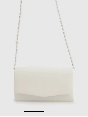 Vit kuvertväska  - Liten vit väska med kedja som går att ta av. Väskan är i nyskick då den endast är använd en gång.