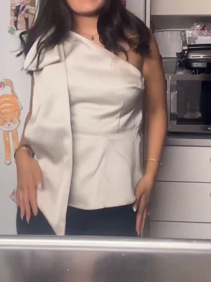 Champagnefärgad oneshoulder topp - Säljer en champagnefärgad oneshoulder topp med en rosett på axeln ❣️ perfekt festtopp! skriv för mer bilder 🤗 har endast använt den en gång!