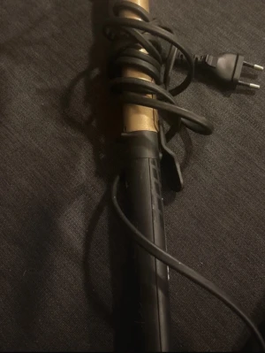 BaByliss locktång med digital display - Säljer en svart och guldig locktång från BaByliss med digital temperaturdisplay. Temperaturen kan justeras mellan 160°C och 200°C. Handtaget är svart med guldfärgad knapp och tydlig logga. Perfekt för att fixa snygga lockar snabbt. Hela locktången är ca 33 cm