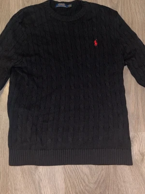 Polo Ralph Lauren tröja - Klassisk svart kabelstickad tröja från Ralph Lauren. Den sitter som en M fast står L på tröjan. Det är pga att den är tvättad. Den är använd ett fåtal gånger utan defekter. Priset är fast