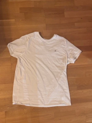Vit t-shirt från Tommy Hilfiger - Klassisk vit t-shirt från Tommy Hilfiger med liten broderad logga på bröstet. T-shirten har rund hals och korta ärmar, perfekt till jeans eller shorts. Tillverkad i mjuk bomull för skön känsla hela dagen.