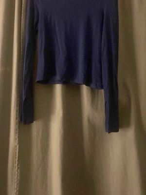 Mörkblå långärmad topp från Cubus - En enkel och stilren mörkblå långärmad topp från Cubus i storlek 158/164. Toppen har en croppad passform och är tillverkad i mjuk bomull, perfekt att matcha med jeans eller kjol för en clean look.
