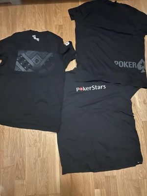 3 Svarta PokerStars t-shirts - Tre svarta t-shirts från PokerStars med olika tryck och loggor. En har ett grafiskt mönster på bröstet, en har stor text och symbol nertill och en har PokerStars-loggan i vitt och rött framtill. Klassisk passform och rund hals, perfekta för pokerfans. 250 för alla tre tröjor!!