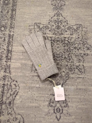 Grå stickade handskar Vivienne Westwood - Säljer ett par grå stickade handskar från Vivienne Westwood med det ikoniska orb-emblemet broderat på mudden. Handskarna har ett diskret mönster och ribbad kant, perfekta för att hålla värmen med stil.
