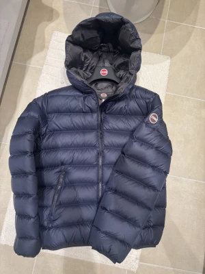 Colmar jacka  - Säljer en mörkblå dunjacka från Colmar med huva och dragkedja. Jackan har quiltad design, två sidofickor med dragkedja och Colmar-logga på ärmen. Perfekt för kalla dagar och riktigt snygg till både jeans och sneakers. Tröjan är använd några gånger, blev snabbt för liten. Pris kan diskuteras 
