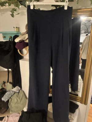 Mörkblå vida byxor från Stockh LM - Säljer ett par mörkblå byxor från Stockh LM i storlek 38. Byxorna har en hög midja och ett rakt, lite vidare ben som ger en chill och stilren look. Perfekta att styla med sneakers eller boots. Materialet känns mjukt och bekvämt.