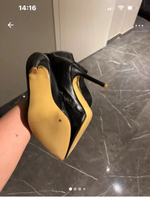 Svarta höga stövlar med klack - Säljer ett par svarta höga stövlar i skinnimitation med spetsig tå och smal hög klack. Snygg siluett som går upp över knät och dragkedja på insidan för enkel påtagning. Perfekta till en statement-look.