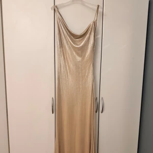 Champagnefärgad balklänning  - En sååå fin balklänning. Klänningen har en glittrig finish och en draperad halslinje. Klänningen är hellång till golvet. Super fin verkligen, använd en gång 🌸🌸🥹