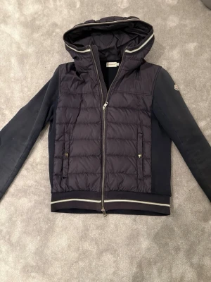 Moncler cardigan - Tja! Säljer nu denna riktigt snygga cardigan från Moncler. Jackan/ cardigan är i storlek M men passar dig som bär storlek S. Jackan har även några hål men som är lagade av en skräddare, kom privat för bild. Denna jacka säljer jag för endast 1999, alltså en riktigt bra deal. Kan gå ner i pris vid snabb försäljning. Vid frågor eller funderingar är det bara att skriva:) // självklart är jackan äkta!
