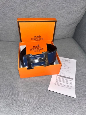 Blått H bälte med silver spänne - Ett blått H bälte med silver spänne. Allt på bilden medföljer 