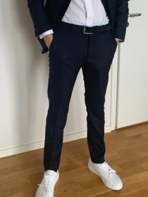 Mörkblå randiga kostymbyxor - Snygga mörkblå kostymbyxor med tunna vita ränder från Riley .Perfekt för en clean och stilren look. Ser ut som nya!!