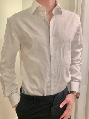 Vit skjorta från Dressmann - Klassisk vit skjorta från Dressmann. Passar i alla garderober till den som vill ha något för uppklädda tillfällen. Perfekt för dig som gillar en clean och enkel look. Storlek XS slim fit