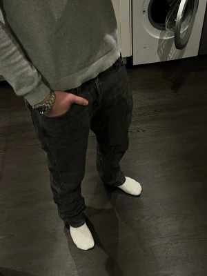 Schyssta Jeans från JJ - Schyssta gråsvarta jeans från Jack And Jones i klassisk straight modell. De är i storleken 31/34. Jeansen har fem fickor och en rak passform, perfekta till en lite schysstare stil. Jeansen är tillverkade i slitstarkt denimtyg som ger en cool look. Om du är ute efter ditt nya par jeans så är dessa det, vid minsta lilla fundering så är det bara att höra av sig🙂