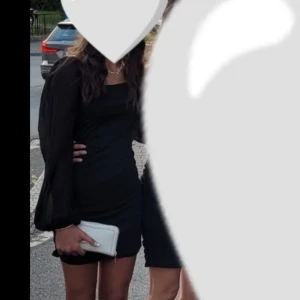 Svart kort klänning med puffärmar - Säljer en svart kort klänning med långa, transparenta puffärmar och fyrkantig urringning. Klänningen har en tight passform och är perfekt för dig som gillar en stilren och trendig look. Materialet är mjukt och följsamt, vilket gör den superbekväm att bära. Endast använd en gång på ett bröllop. 