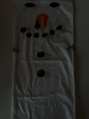 Vit halsduk med snögubbe-motiv - Rolig vit halsduk med tryck av snögubbeansikte, morotsnäsa och svarta knappar. Perfekt accessoar för vinter och jul, ger en lekfull touch till din outfit. Mjuk och lätt material som känns skönt runt halsen.